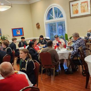A group of people gathered around tables at an indoor dining event.