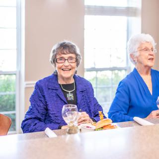 Two elderly women enjoying a meal together at a dining table.