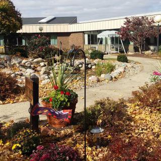 A scenic view of a building surrounded by an autumn garden with colorful foliage and a winding pathway.