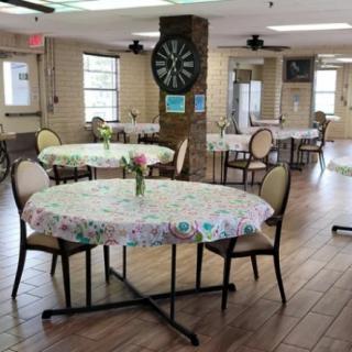 A cozy dining area with floral tablecloths and a dartboard on the wall.
