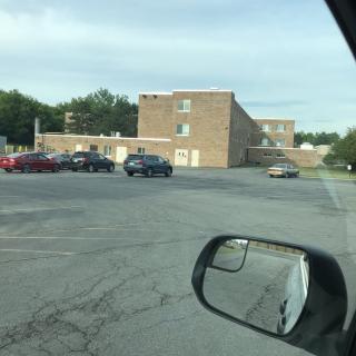 A view of a brick building with a parking lot containing several cars.