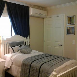A cozy bedroom with a single bed, dark curtains, and an air conditioner.