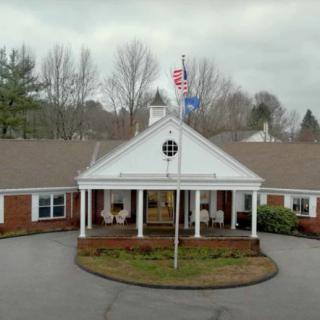 A building with a covered entrance and flags flying on an overcast day.