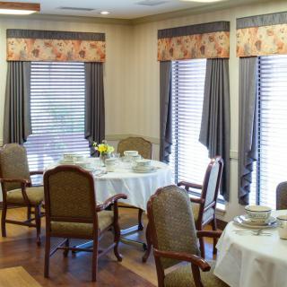 A cozy dining room setup with round tables, chairs, and large windows.