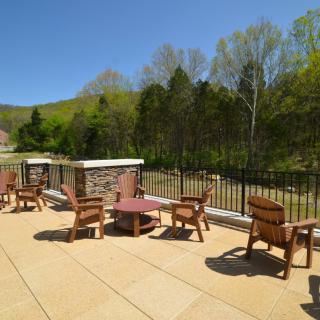 A scenic outdoor patio with wooden chairs and tables overlooking a natural landscape.