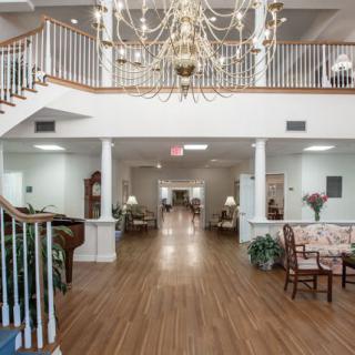 Spacious lobby with a grand chandelier, staircase, and elegant furnishings.