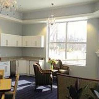 A bright and modern kitchen interior with white cabinets, a large window, and elegant seating.