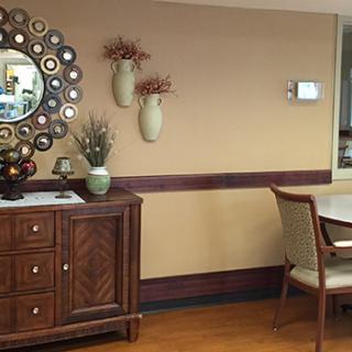 Stylish interior with wooden furniture, decorative wall mirror, and vases on a beige wall.