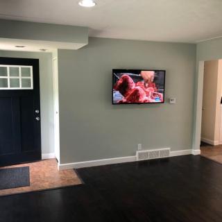 A minimalist living room with a wall-mounted television and dark hardwood flooring.