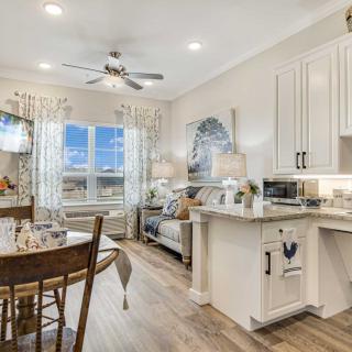 A cozy and modern open floor plan with a living room, kitchen, and dining area featuring wood flooring and ample natural light.