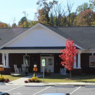Small building with a parking area and autumn trees.