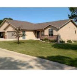 A suburban single-story house with a well-maintained lawn and driveway.