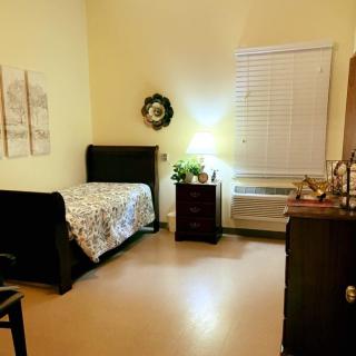 Cozy bedroom with a single bed, nightstand, and warm lighting.