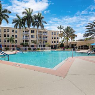 A serene outdoor pool area surrounded by palm trees and a residential building.