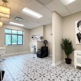 A modern hair salon with stylish decor, featuring a comfortable chair, artwork, and patterned tile flooring.