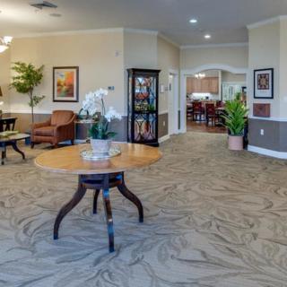 A well-decorated lobby area featuring a central table with a plant, elegant lighting, and seating arrangements near the walls.