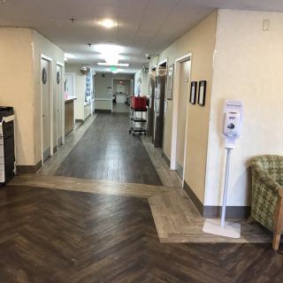 A clean and empty hospital corridor with a sanitizer dispenser.