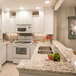 A modern kitchen with white cabinets and granite countertops.