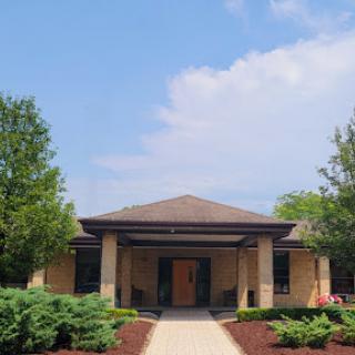 A modern building surrounded by lush greenery and a clear blue sky.