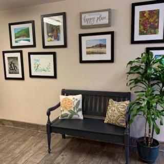A cozy waiting area with wall art and a bench.