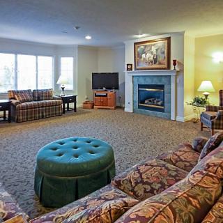 A spacious living room with a fireplace, sofas, and large windows.