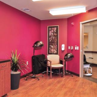 A cozy salon interior featuring vibrant red walls, seating, and hairdryers.