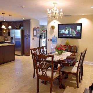 A cozy dining area with a view into the kitchen, featuring elegant wooden furniture and a chandelier.