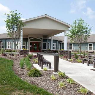 A well-maintained building entrance with a landscaped garden and benches.