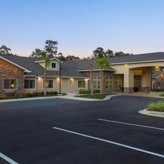 A modern residential building with a spacious parking lot and landscaped surroundings.