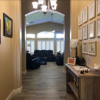 A cozy hallway leading to a living room, adorned with certificates and a small table.