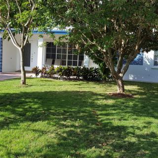 A suburban house with a well-maintained yard and trees in bright sunlight.