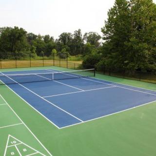 An empty outdoor tennis court surrounded by trees.