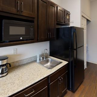A compact kitchen featuring dark wood cabinets, a microwave, and a coffee maker on the countertop.