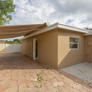 A small house with a patio area featuring an awning and stone path.