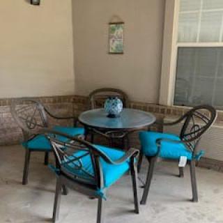 A cozy patio setup with a round table and four chairs featuring blue cushions.