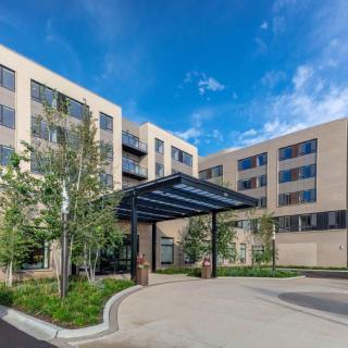 A modern residential building with a covered entrance and landscaped surroundings.
