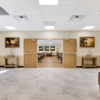 A spacious hallway featuring doors leading to a dining area, decorated with artwork on the walls.