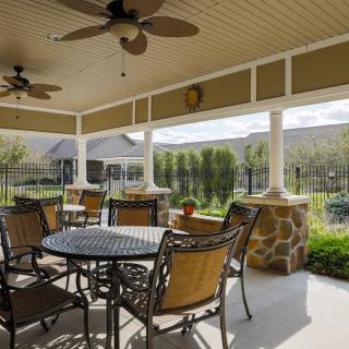 A cozy outdoor patio with ceiling fans, surrounded by lush greenery.