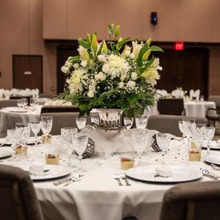 An elegantly set banquet table adorned with a floral centerpiece, suitable for a wedding or formal event.