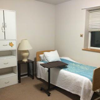 A simple, minimalist room with a hospital bed and basic furniture.