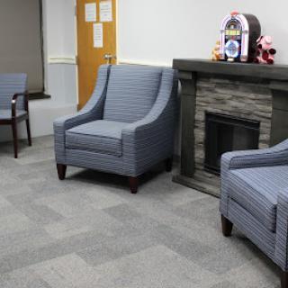A cozy waiting area featuring two blue upholstered chairs and a decorative fireplace.