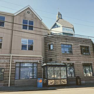 A modern building with distinctive architectural features and a bus stop in front.