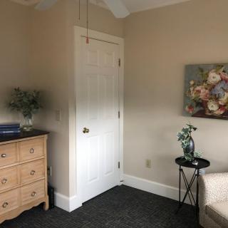 A cozy bedroom corner featuring a dresser, side table with a plant, and wall art.
