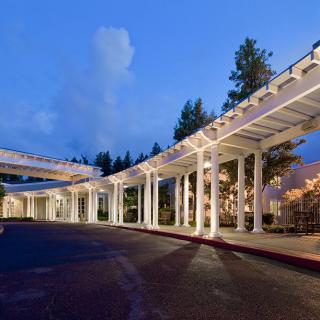 A modern hospital building with a covered walkway, illuminated at night.