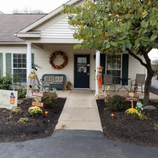A cozy house entrance decorated with autumn-themed elements and seasonal plants.