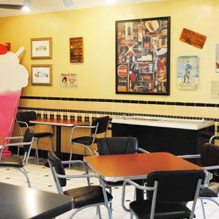 A retro-style diner interior featuring tables, chairs, and nostalgic decor.