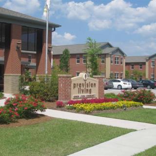 An apartment complex with neatly arranged landscaping and a central sign in a residential area.