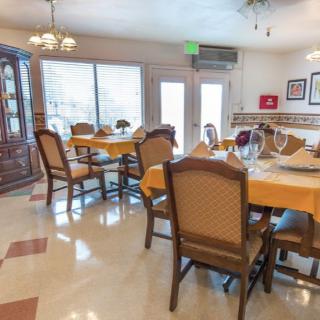 An inviting dining area with several tables and chairs, well-lit by natural light through large windows.