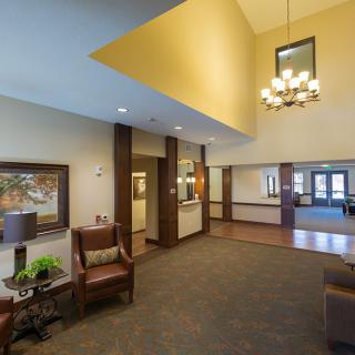 A well-lit lobby with comfortable seating, artwork on the walls, and a chandelier hanging from the ceiling.