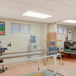 A well-equipped physical therapy room featuring parallel bars and an exercise bike.